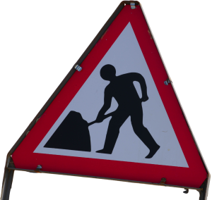 A UK roadworks sign - it is a red triangle with the depiction of a person digging in the middle in black & white